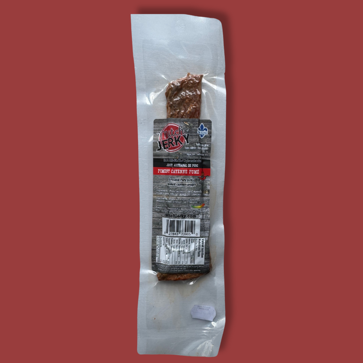Emballage de jerky artisanal de porc Mitch Jerky, saveur piment cayenne fumé. Produit québécois sous vide avec certification Aliments du Québec. Collation riche en protéines, au goût épicé et fumé, parfaite pour les amateurs de viande séchée relevée.